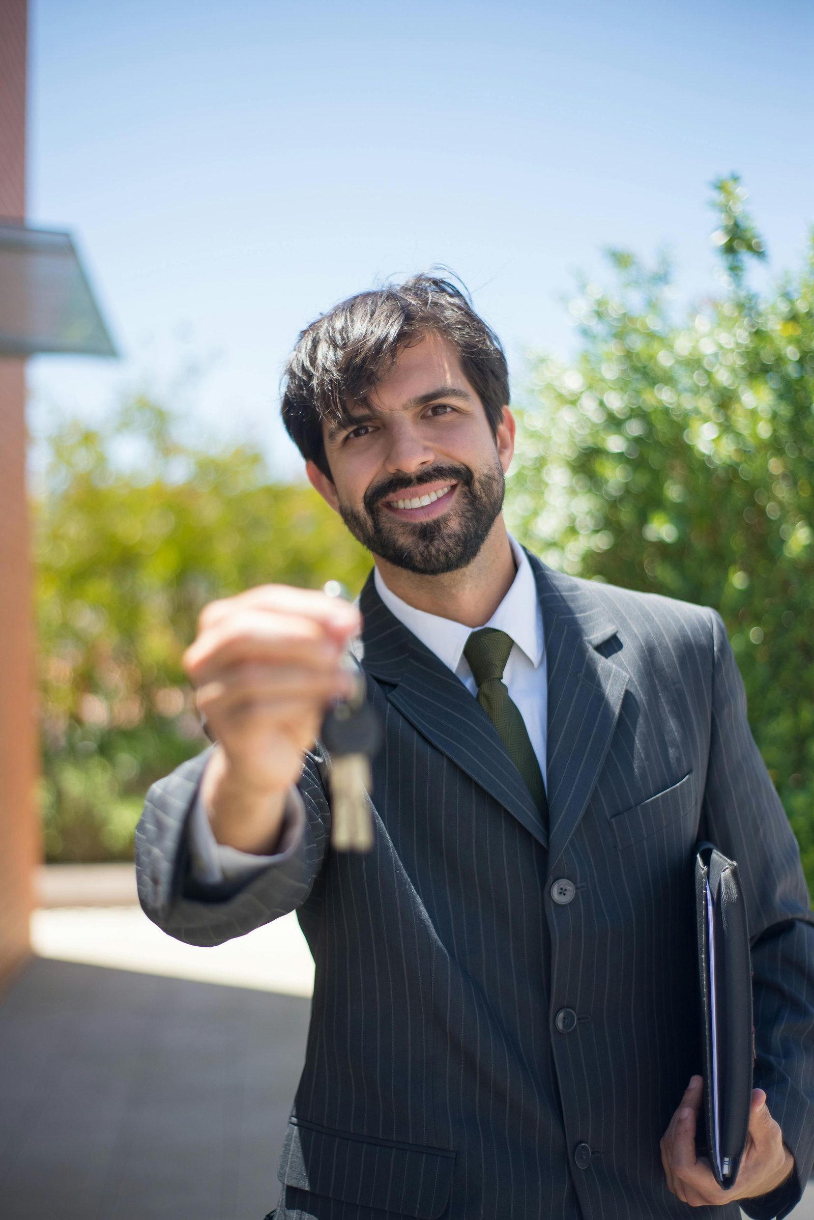 A property agent smiling and holding out a set of apartment keys